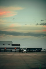 A private jet taxiing on a runway at sunset.