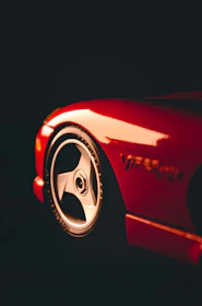 Close-up shot of a red sports car highlighting the detailed design of the velg wheels.
