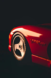 Close-up shot of a red sports car highlighting the detailed design of the velg wheels.