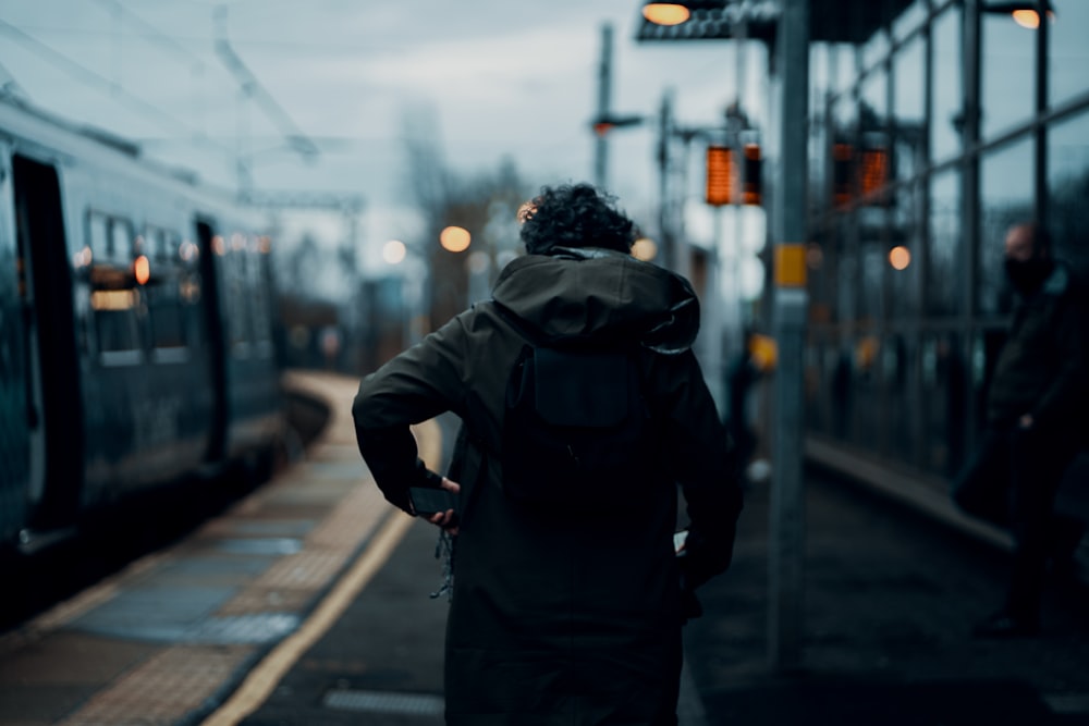 man in black jacket walking on sidewalk during daytime