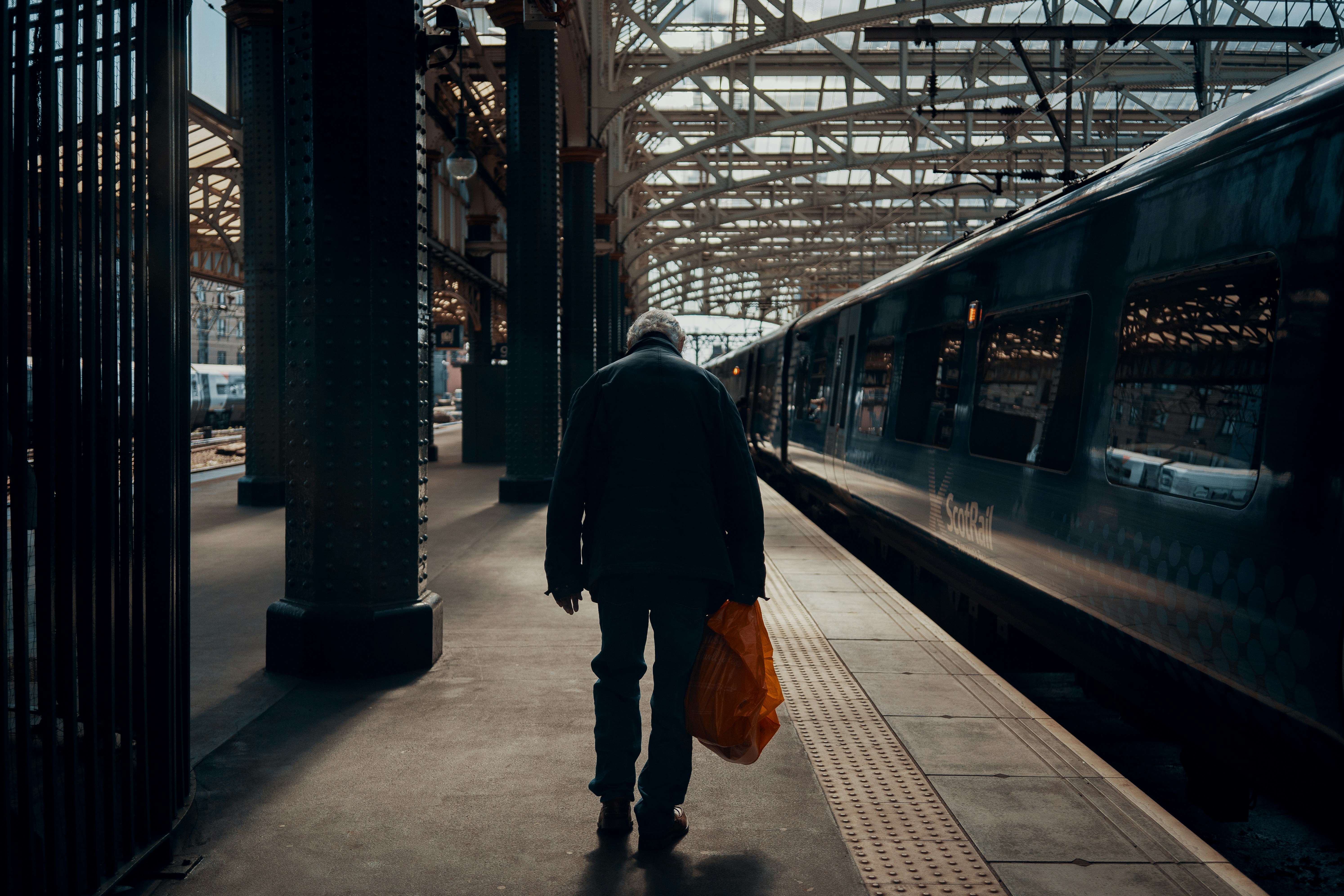 a man with a bag walking towards a train
