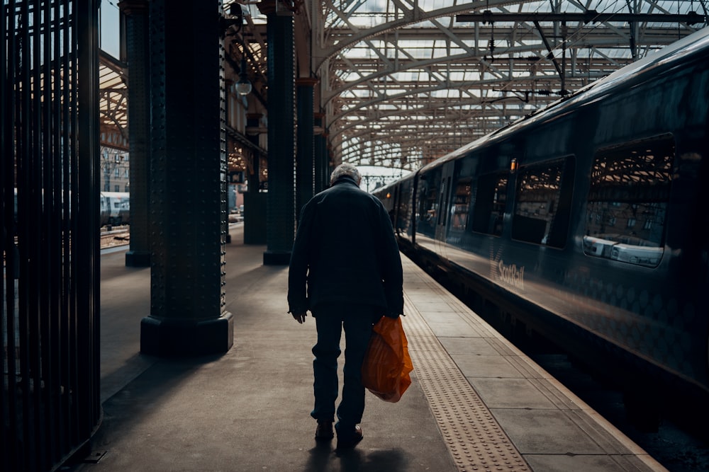 a man with a bag walking towards a train