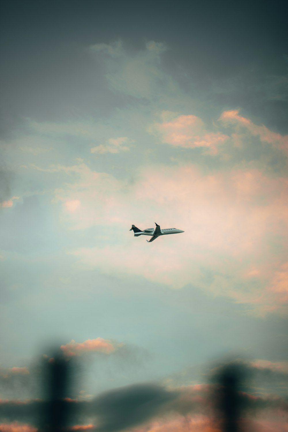 two birds flying under white clouds during daytime