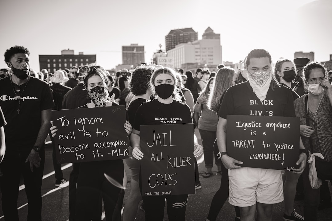 grayscale photo of man in black and white hoodie holding banner