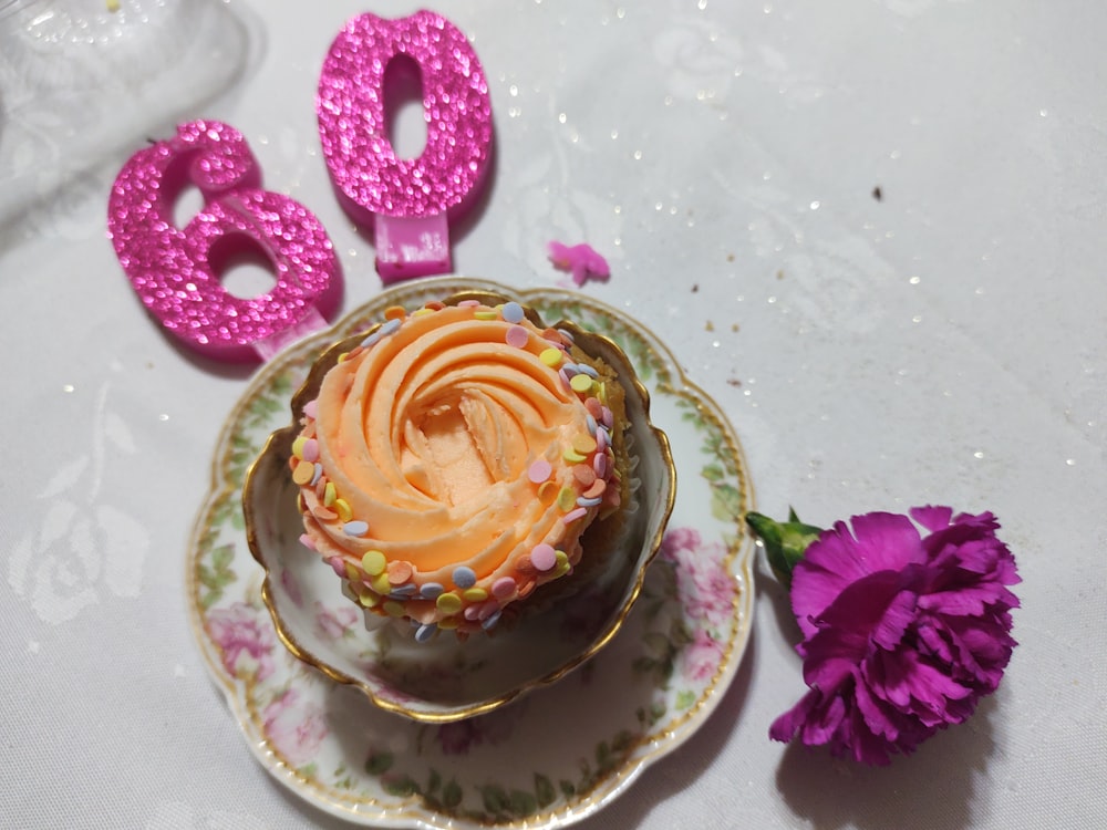 Tarta rosa y amarilla sobre plato de cerámica floral blanca y morada