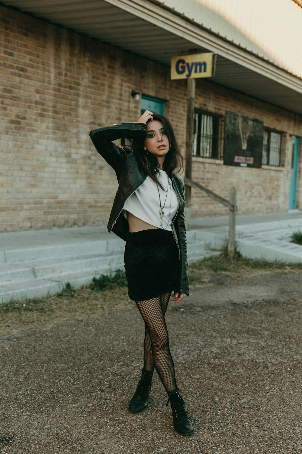 woman in white long sleeve shirt and black skirt standing on sidewalk during daytime