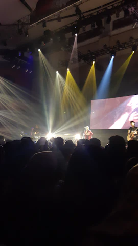 A vibrant live band performing on stage with colorful lights and an enthusiastic crowd.