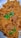 A plate filled with golden-brown rice mixed with chunks of tender meat, garnished with fresh green coriander leaves.