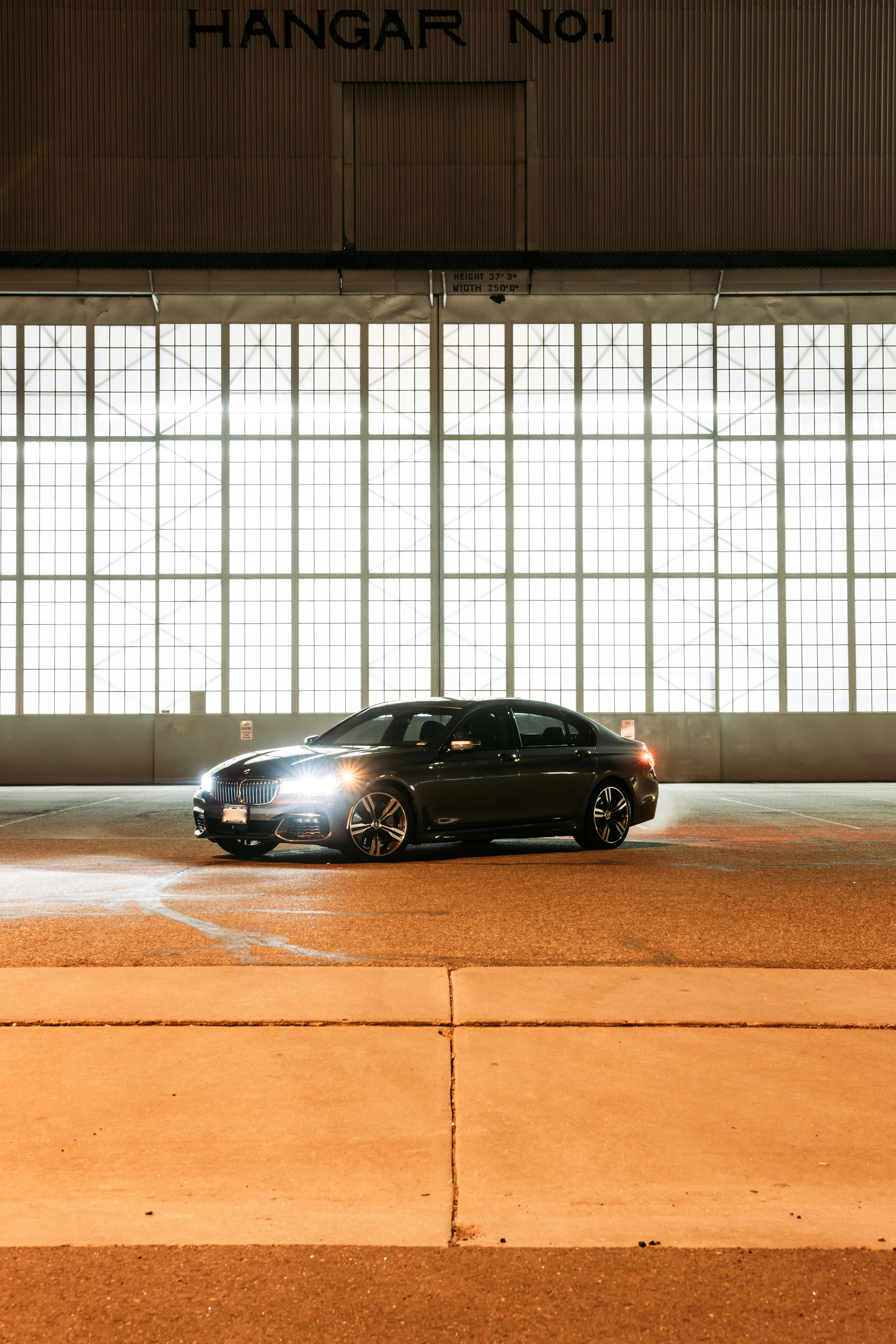 black sedan parked beside white wall