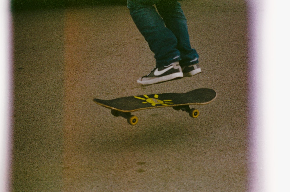 person in blue denim jeans and black and white nike sneakers standing on black skateboard during