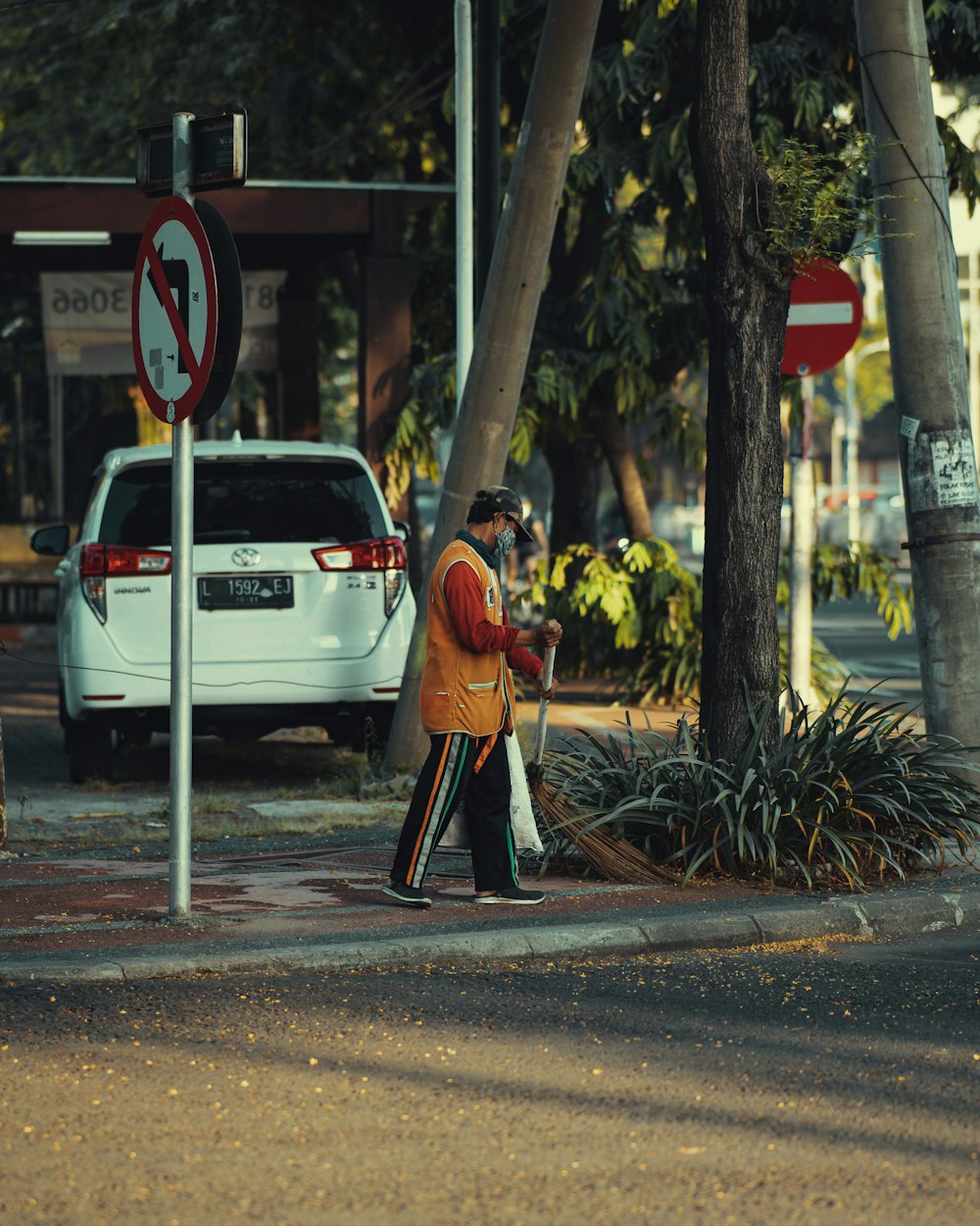 Frau im roten Kittel steht tagsüber auf dem Bürgersteig in der Nähe von White Car