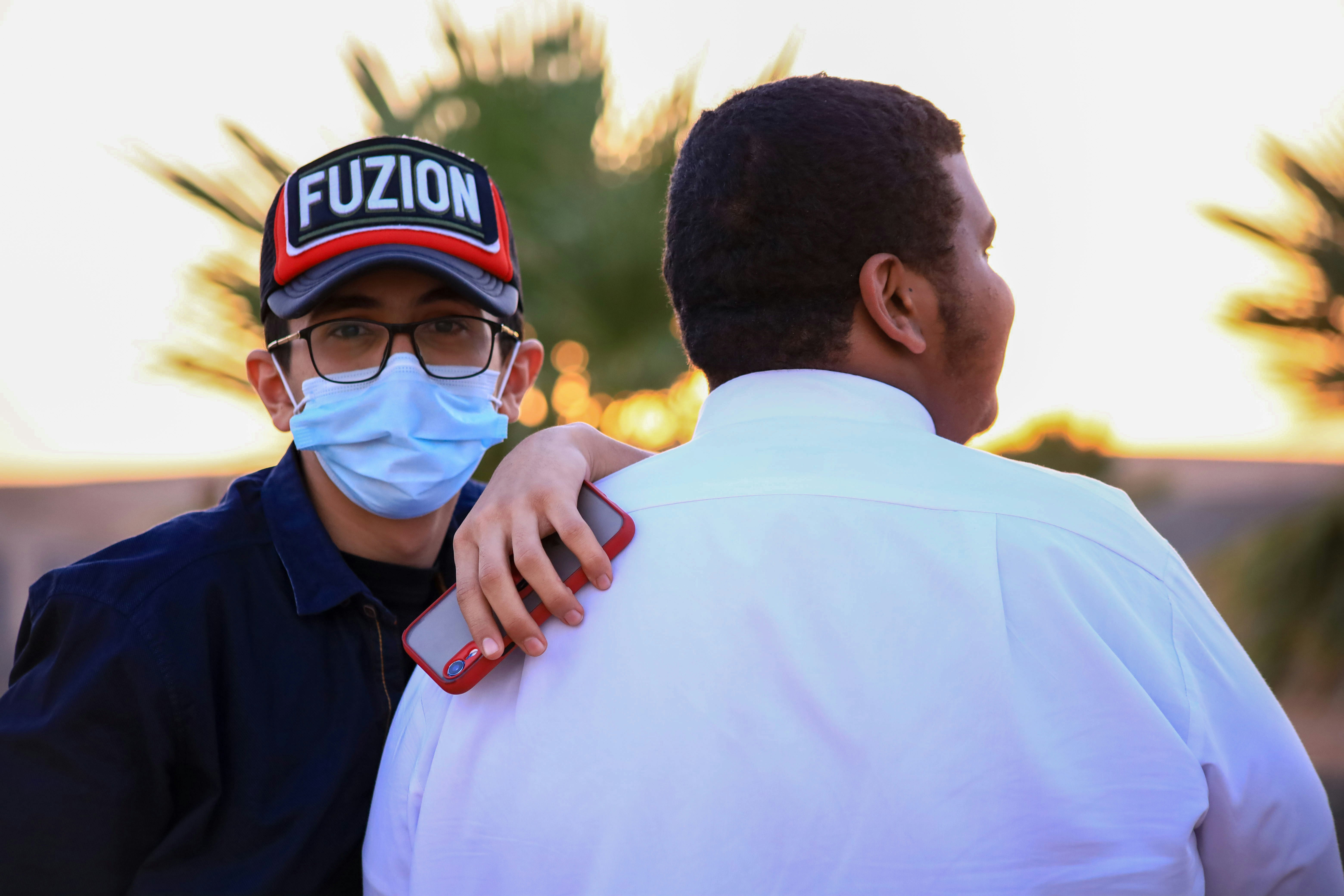 man in white shirt wearing black sunglasses and black cap