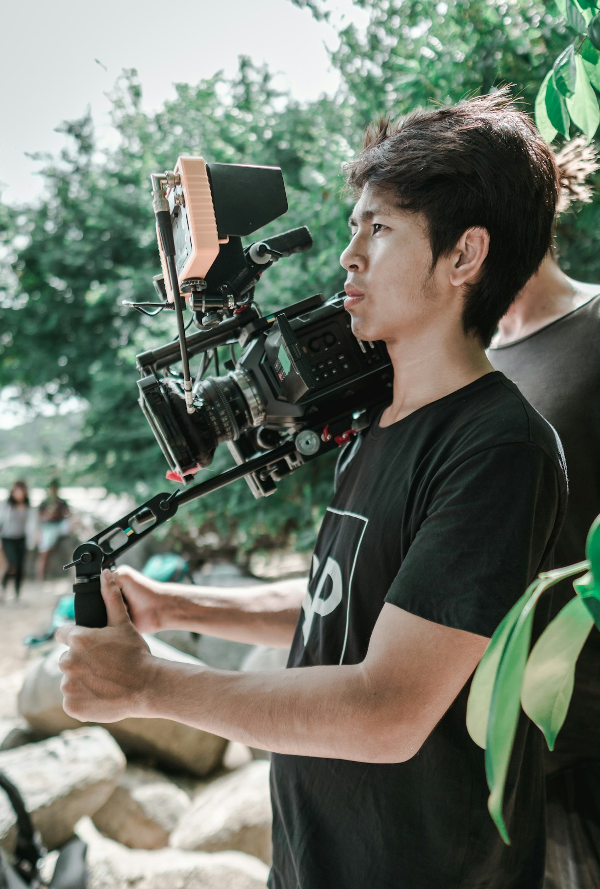 A creative videographer filming a vibrant outdoor event with a professional camera.