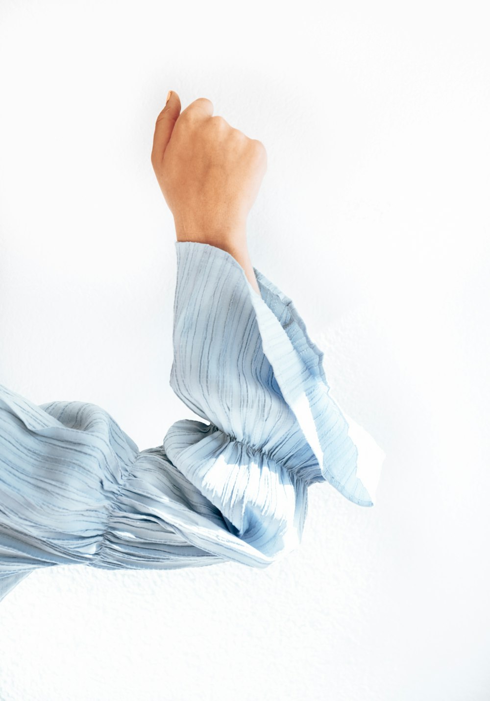 person in white long sleeve shirt lying on white textile