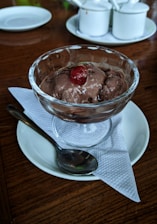 A vibrant bowl of Babe Ice Cream topped with fresh berries and drizzled dark chocolate against a rustic wooden table background.