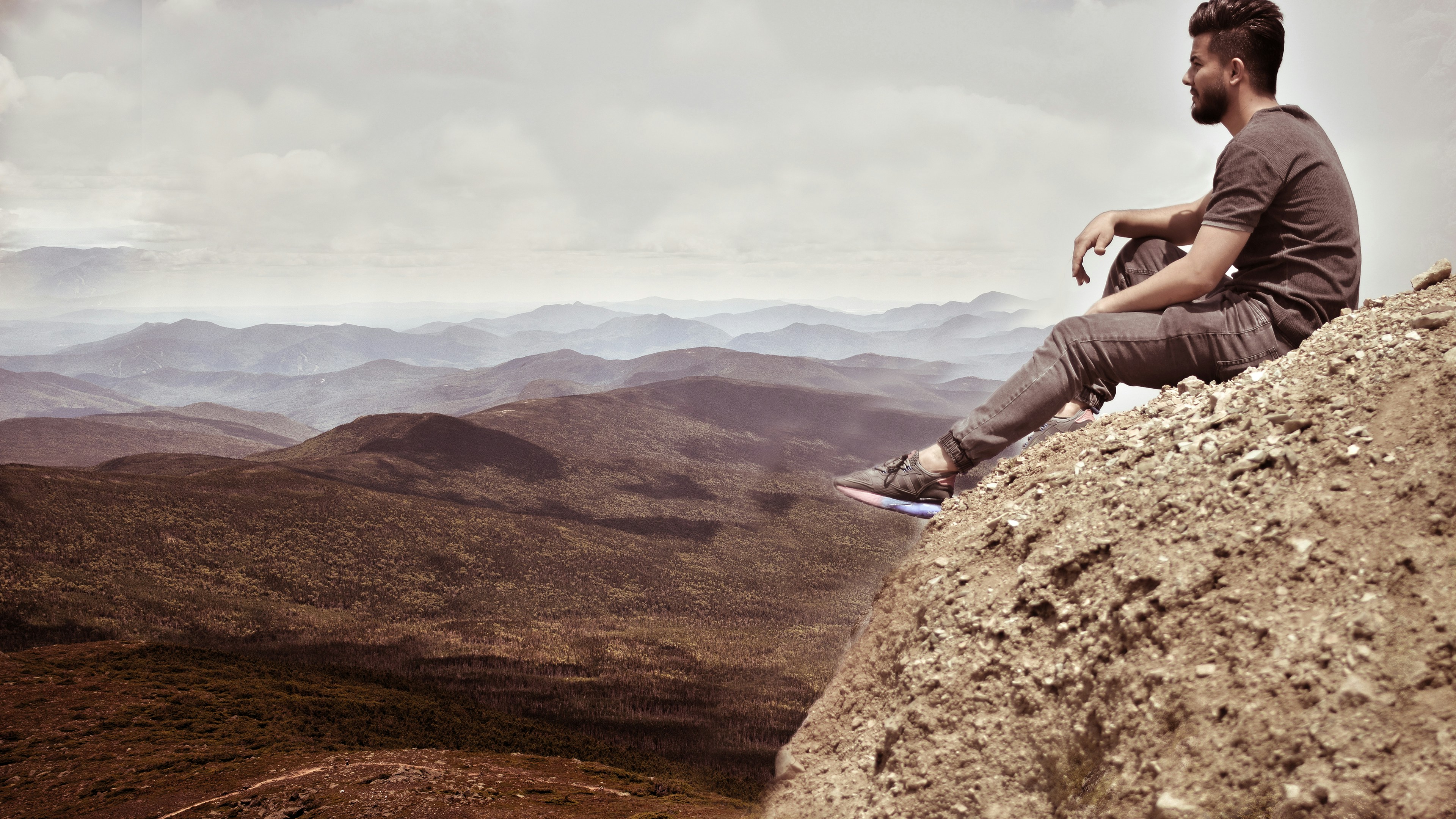 person in gray pants sitting on brown rock during daytime