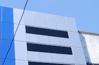 Installation team fitting a large black and blue ACM panel on a storefront