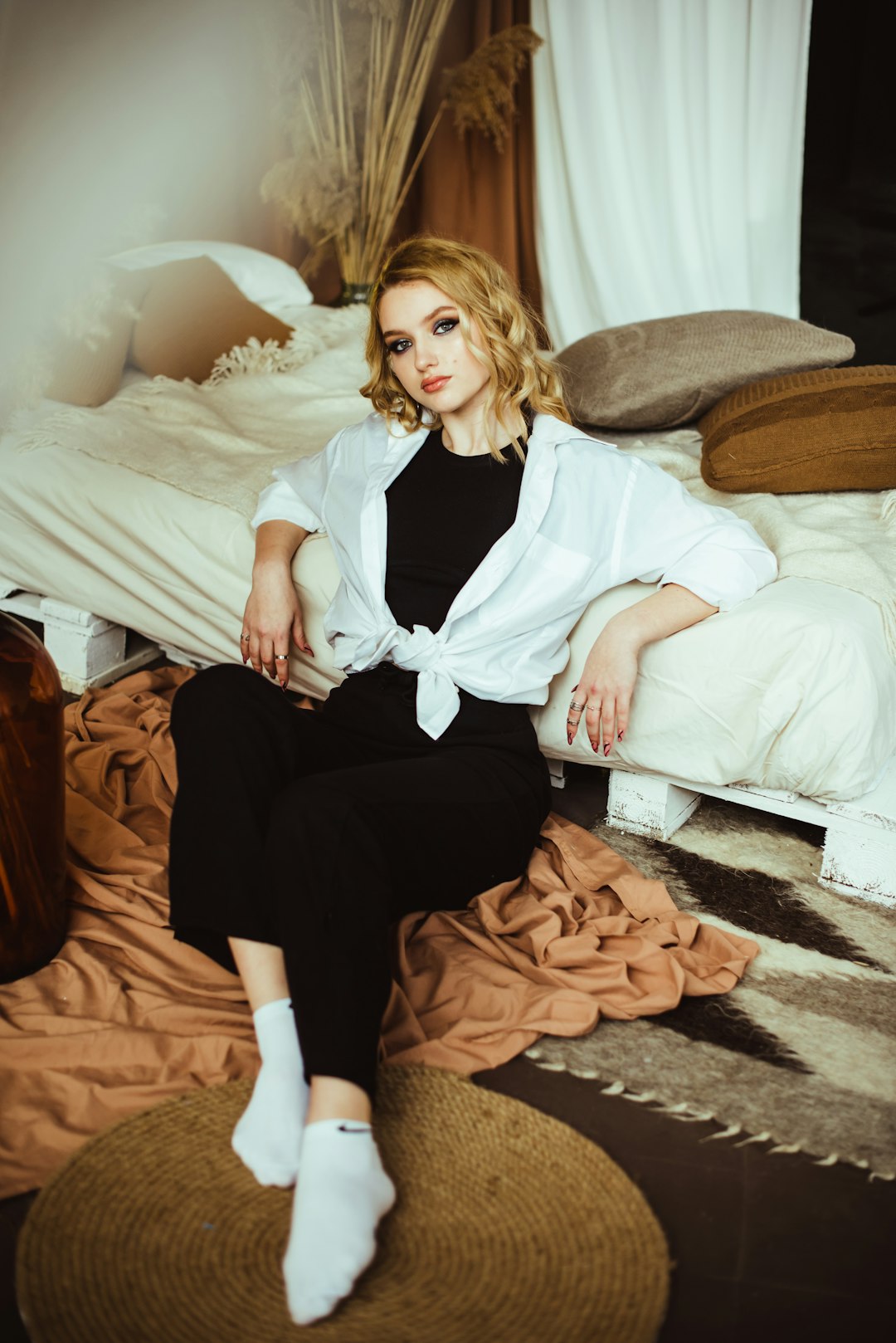 woman in white dress shirt and black pants sitting on bed