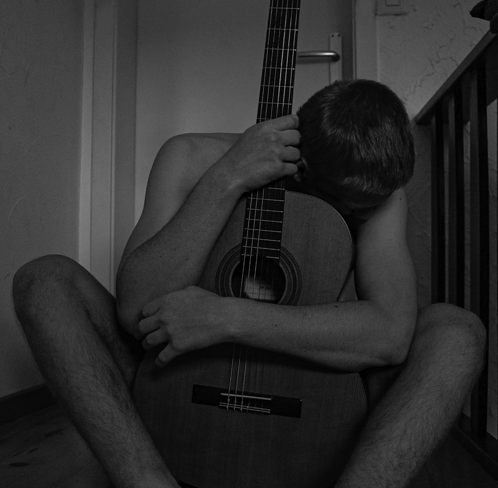 topless man playing acoustic guitar