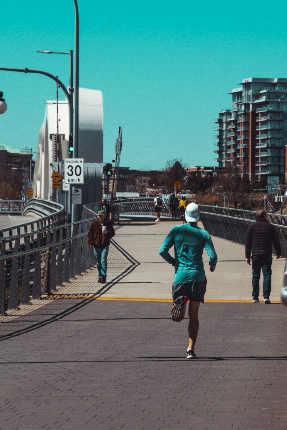 man in blue jacket and brown pants walking on sidewalk during daytime