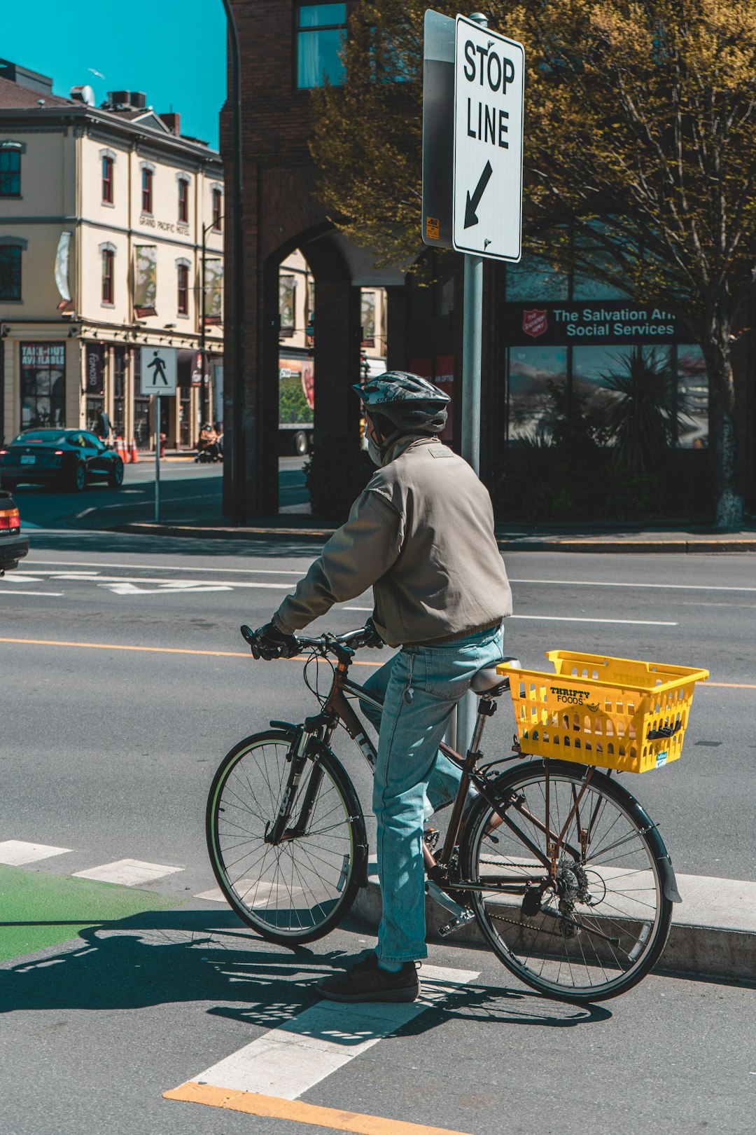man in gray jacket and blue denim jeans riding bicycle on road during daytime