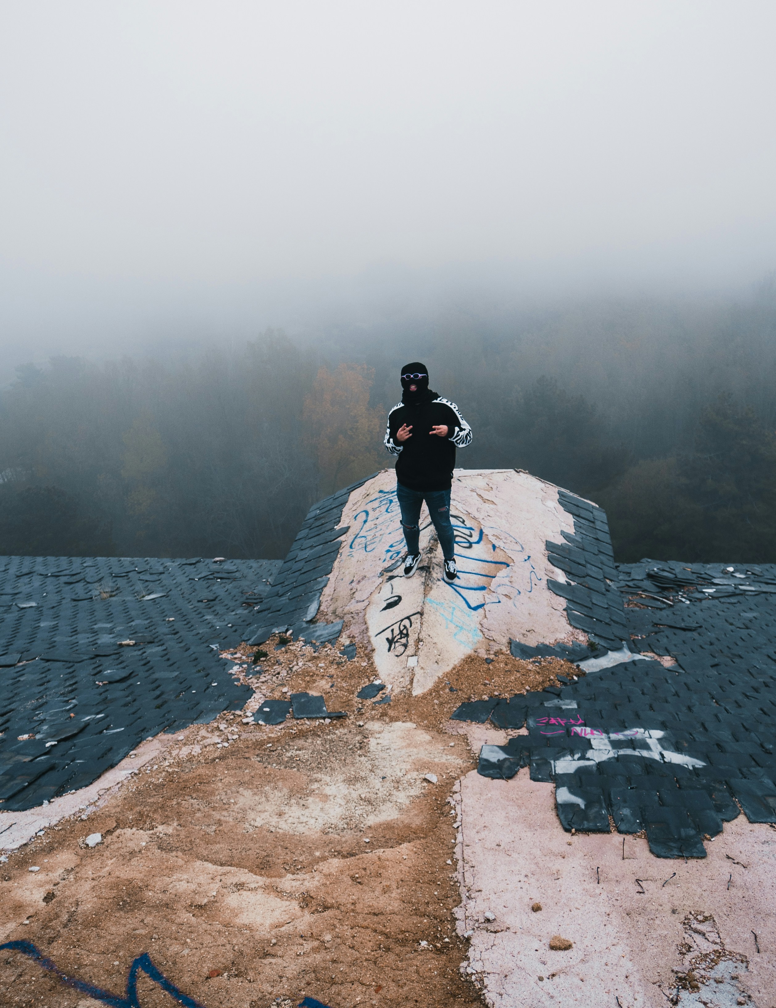 person in black jacket and black pants standing on gray rock formation during daytime