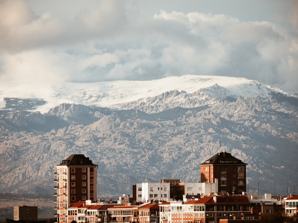 brown and white concrete buildings near snow covered mountain during daytime