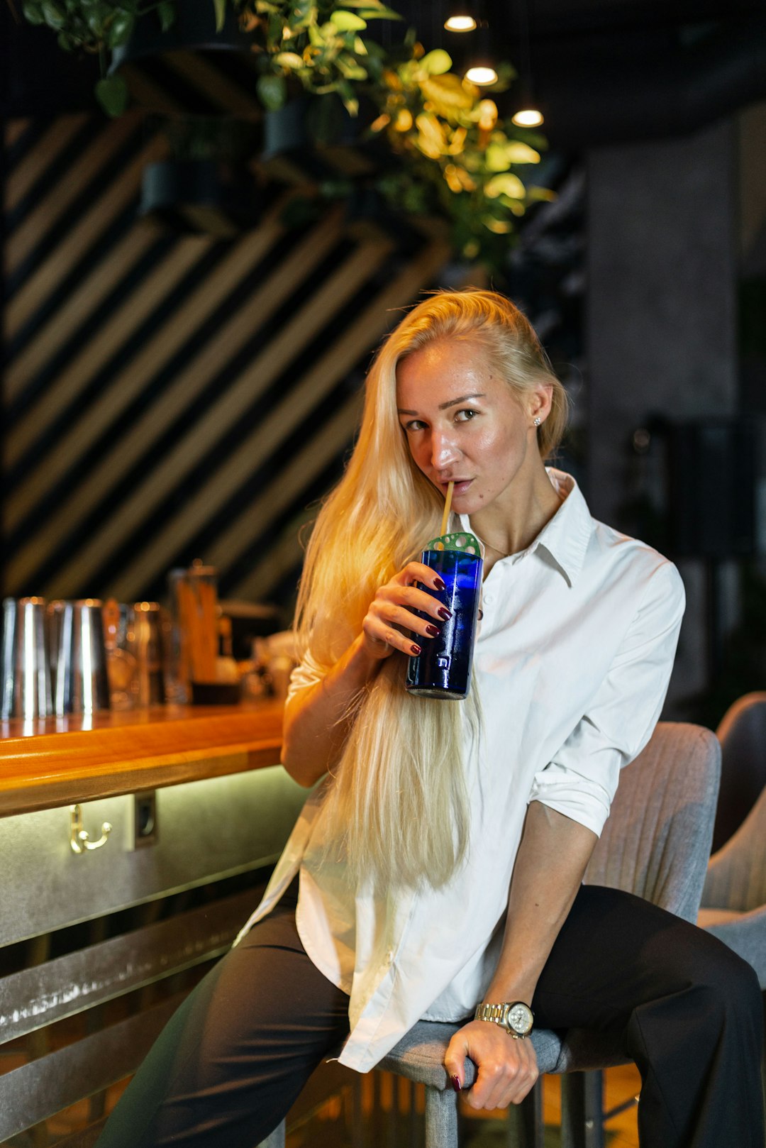 woman in white button up shirt holding blue labeled bottle