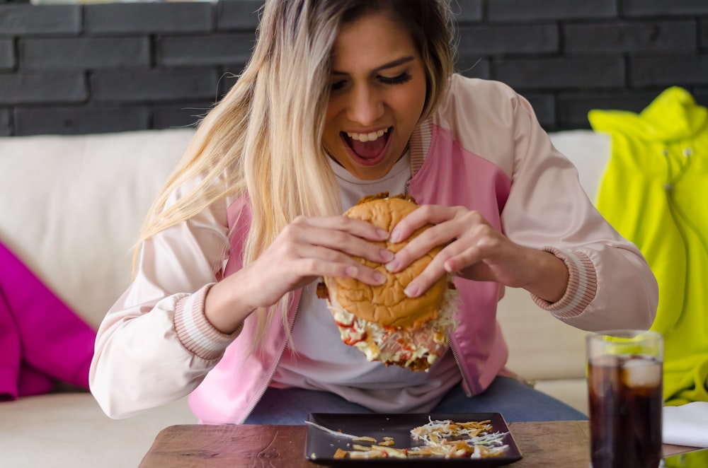 girl in pink long sleeve shirt eating bread