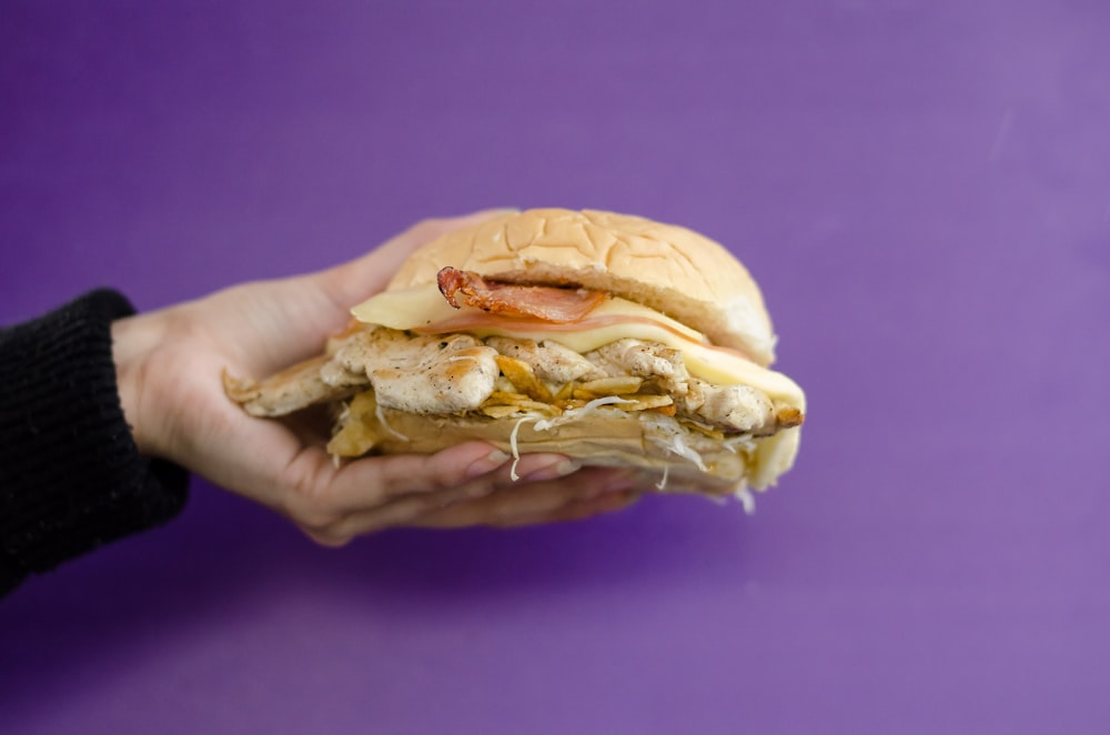 person holding burger with lettuce