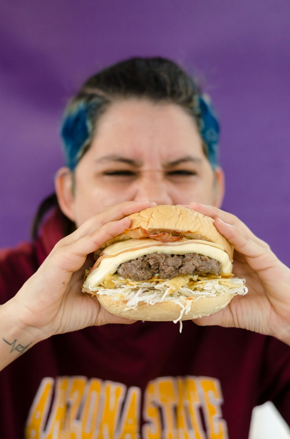 person holding burger with patty and cheese