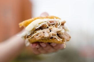 Close-up of a messy, delicious sloppy joe sandwich held in hands, ready to eat.