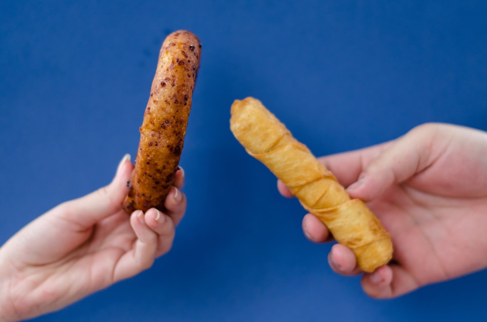 person holding brown food on blue textile