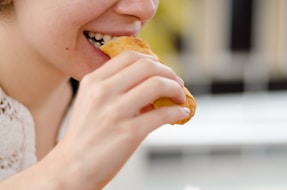woman eating bread during daytime