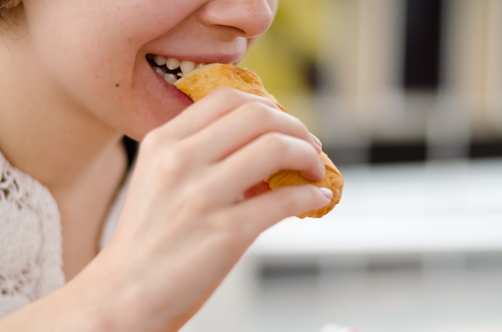woman eating bread during daytime