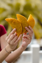 person holding yellow heart shaped Venezuelan pasties