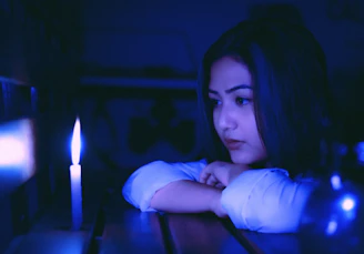 A mature single woman reading a devotional by candlelight, her expression peaceful and reflective.