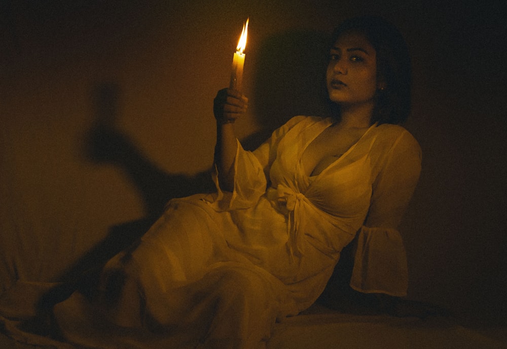 woman in white dress holding lighted candle