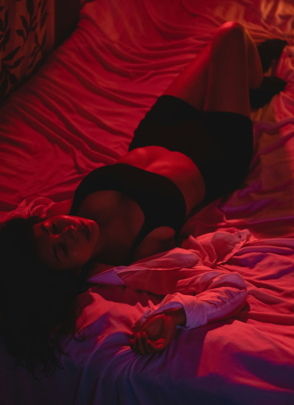 woman in black brassiere lying on bed
