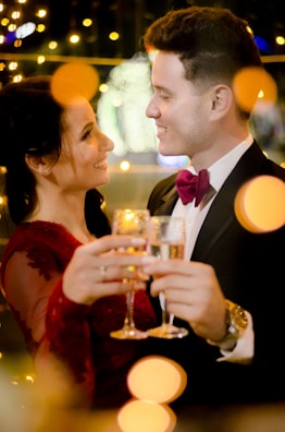A glamorous couple dressed up, striking a pose at the glam photobooth with candy apple red decorations.