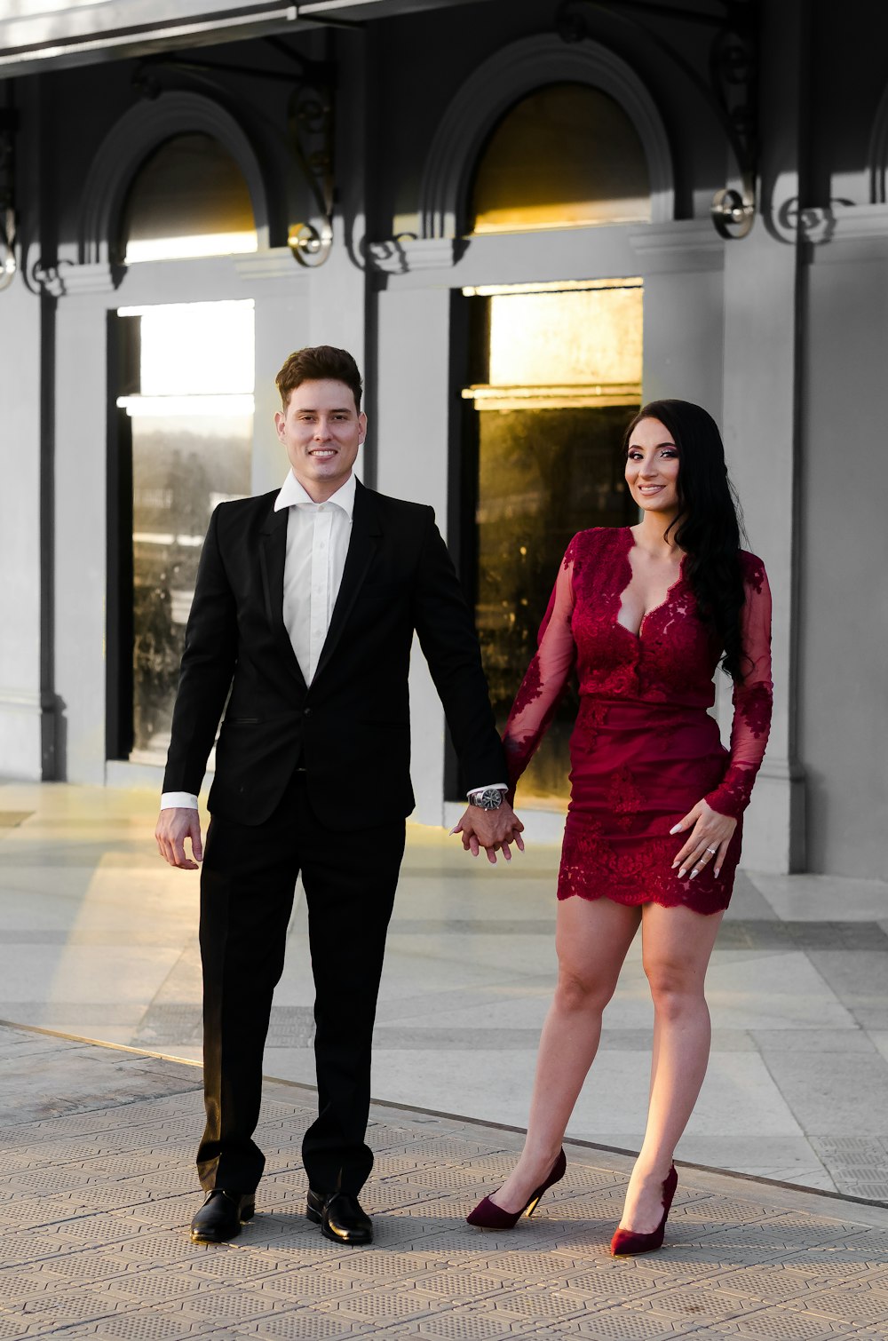 man in black suit standing beside woman in red dress