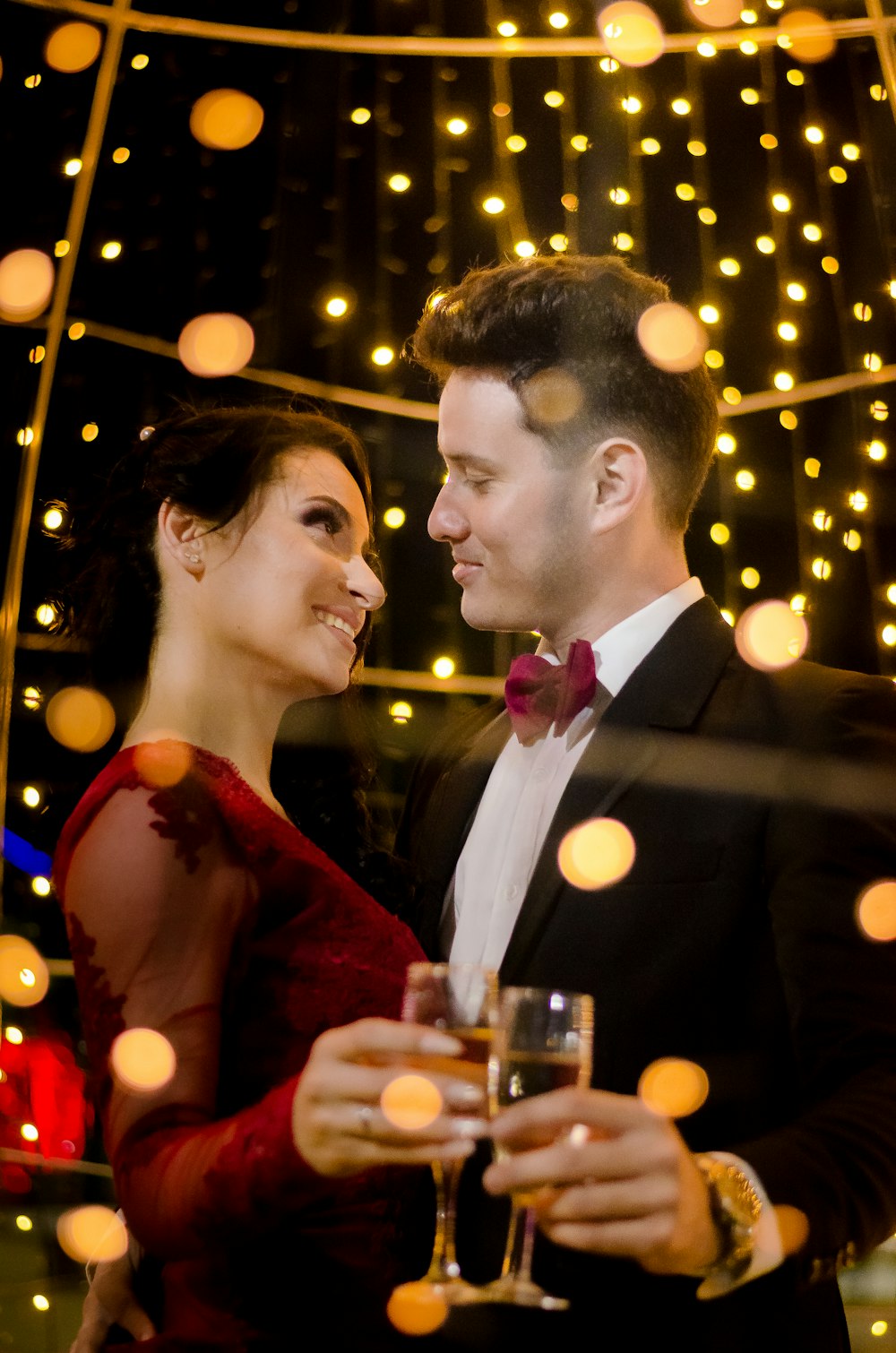 man in black suit jacket kissing woman in red sleeveless dress