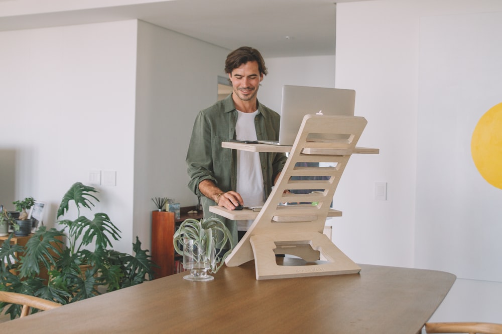 man in gray dress shirt standing beside brown wooden table