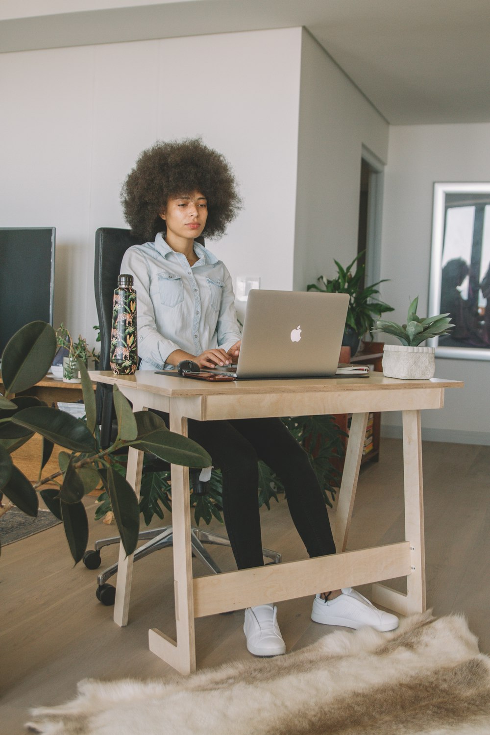 woman in gray jacket sitting on chair using macbook