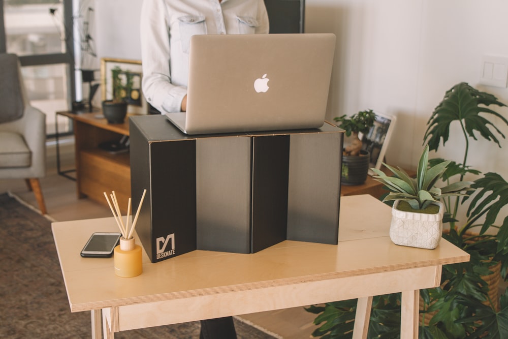 silver macbook on black and white wooden shelf