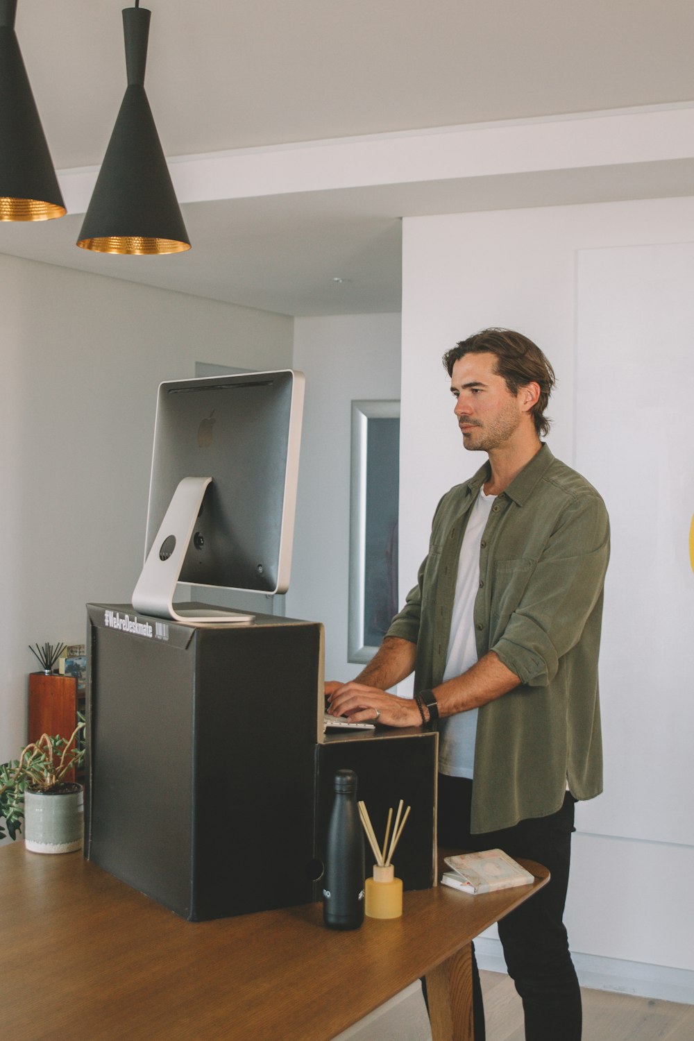 man in gray button up shirt standing near black flat screen computer monitor