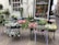 A charming outdoor flower shop displays an array of vibrant plants and flowers. The scene includes various pots filled with blooming flowers and lush greenery. The shop's window showcases decorative vases and floral arrangements, creating an inviting and colorful environment.
