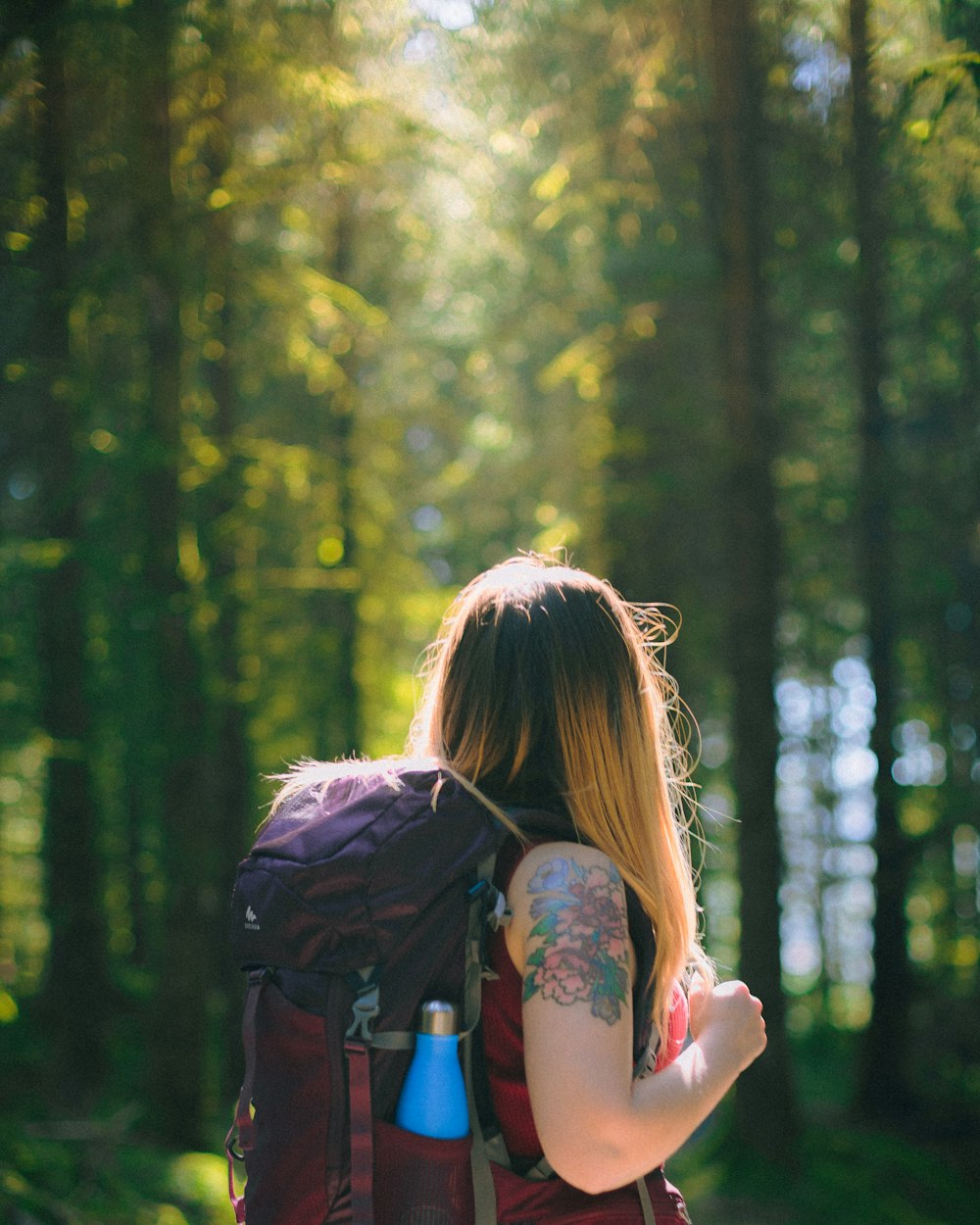 woman in blue and pink floral tank top carrying black backpack