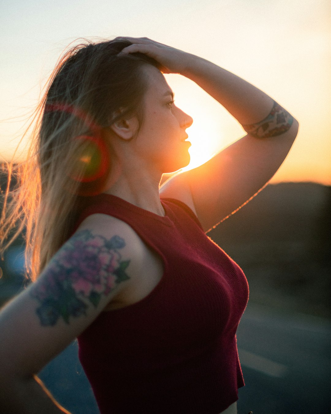 woman in red tank top with black floral tattoo on left arm