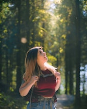 woman in red sleeveless top standing near green trees during daytime